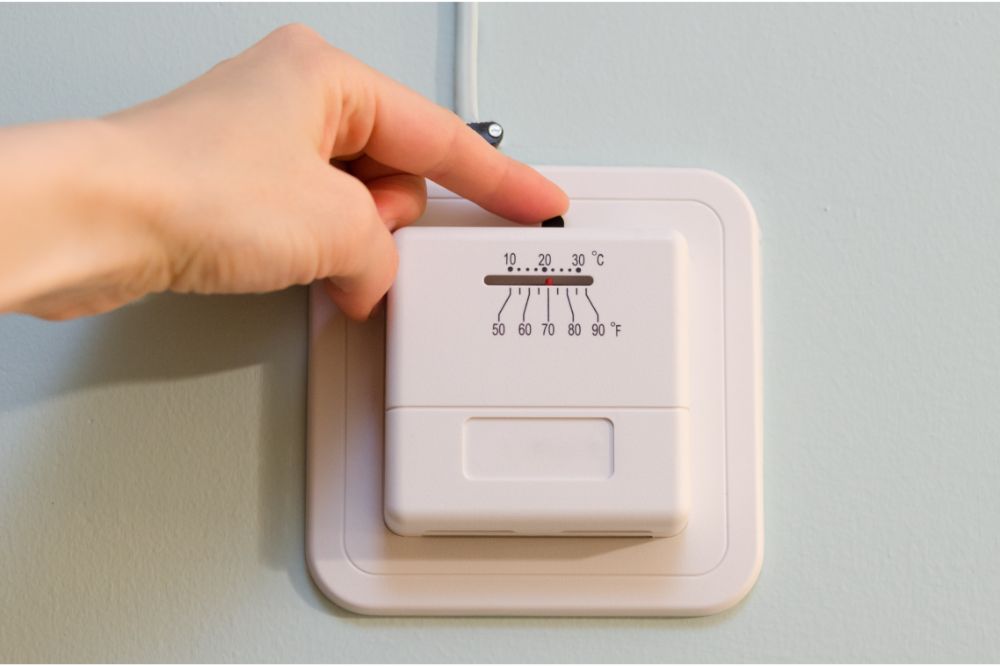 Hand touching thermostat for controlling room temperature
